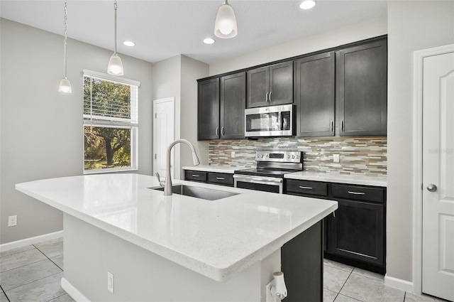 kitchen featuring backsplash, sink, stainless steel appliances, and a kitchen island with sink