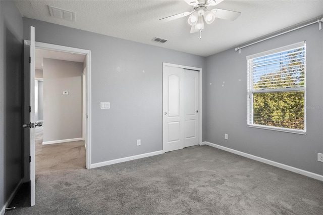 unfurnished bedroom with ceiling fan, carpet flooring, a textured ceiling, and a closet