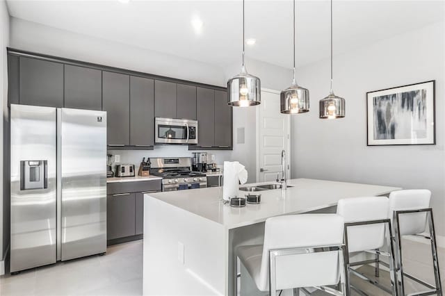 kitchen with a kitchen breakfast bar, pendant lighting, an island with sink, and appliances with stainless steel finishes