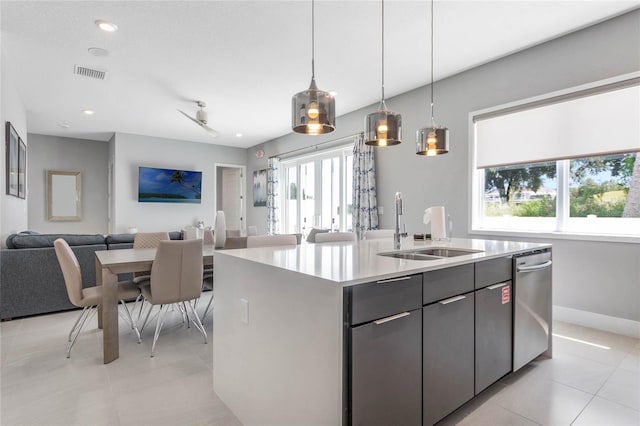 kitchen featuring sink, light tile patterned flooring, pendant lighting, stainless steel dishwasher, and a kitchen island with sink