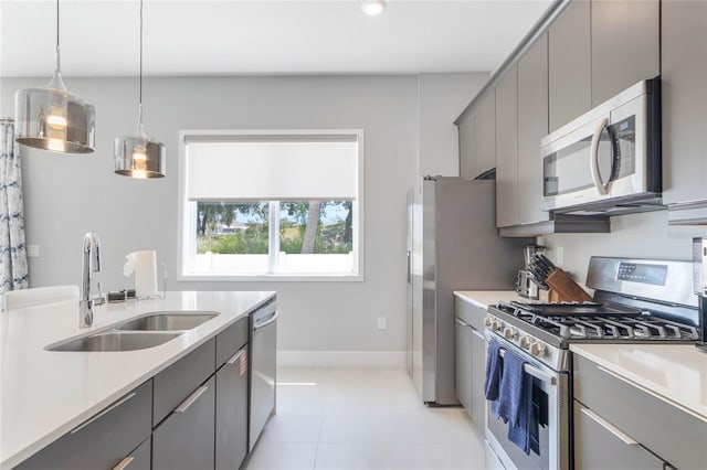 kitchen with gray cabinets, appliances with stainless steel finishes, hanging light fixtures, light tile patterned floors, and sink