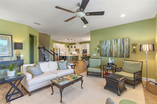 living room with a textured ceiling, light hardwood / wood-style floors, and ceiling fan