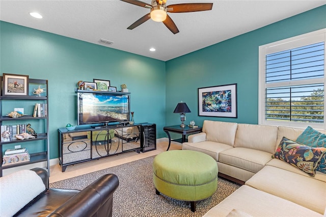 carpeted living room featuring ceiling fan and a textured ceiling