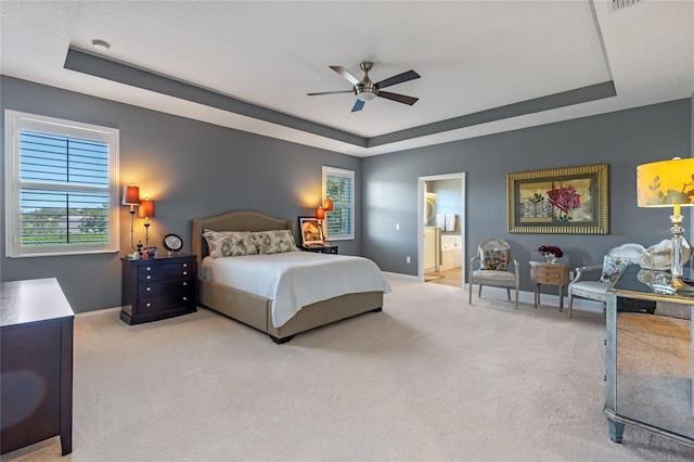 bedroom featuring carpet, ceiling fan, connected bathroom, and a tray ceiling