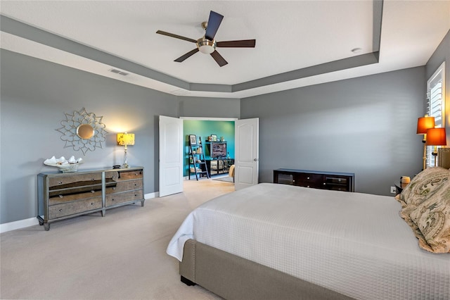 carpeted bedroom featuring a raised ceiling and ceiling fan