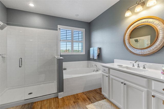 bathroom with wood-type flooring, vanity, and shower with separate bathtub