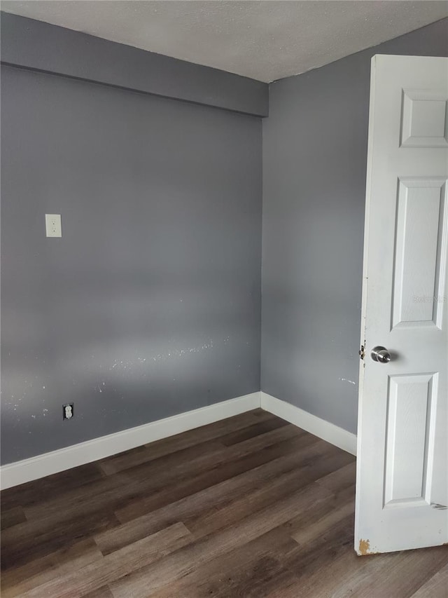 empty room with a textured ceiling and dark hardwood / wood-style flooring