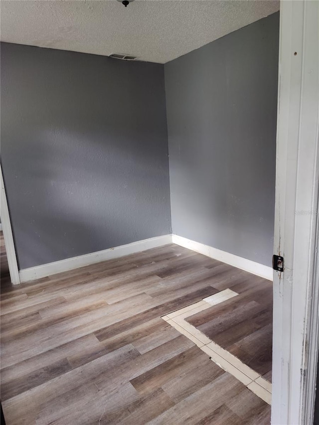 spare room featuring light hardwood / wood-style floors and a textured ceiling