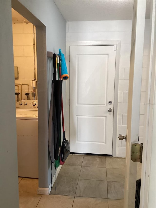 doorway to outside with tile patterned floors, a textured ceiling, and washer / clothes dryer