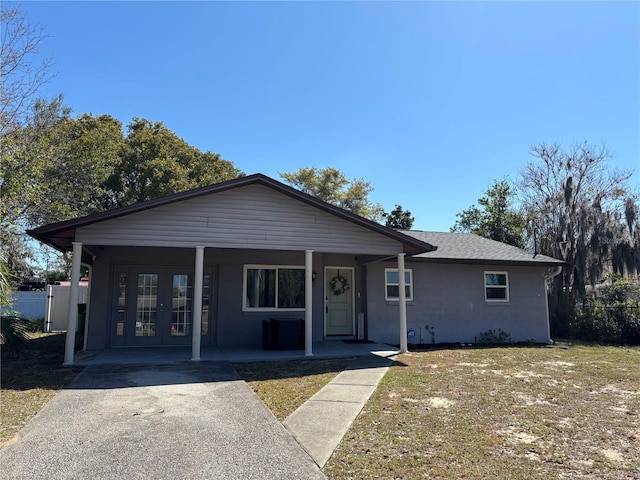 view of front facade with french doors, roof with shingles, covered porch, and fence