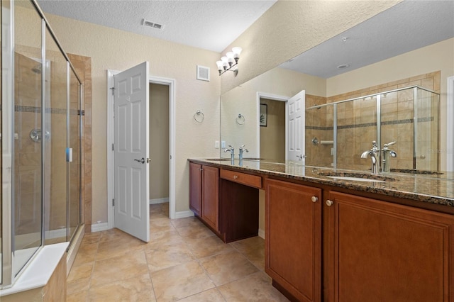 bathroom featuring tile patterned flooring, vanity, a textured ceiling, and walk in shower