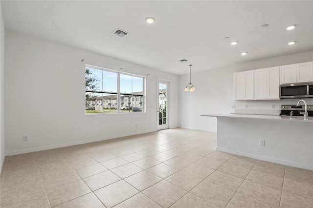 interior space featuring white cabinets, light tile patterned floors, hanging light fixtures, and appliances with stainless steel finishes