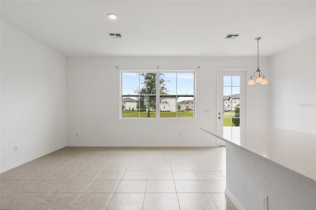 spare room with light tile patterned flooring and an inviting chandelier