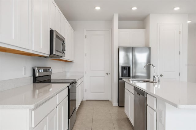 kitchen featuring sink, light tile patterned floors, an island with sink, appliances with stainless steel finishes, and white cabinetry