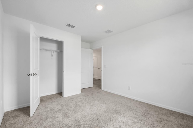 unfurnished bedroom featuring light colored carpet and a closet