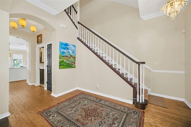 entrance foyer with hardwood / wood-style floors, crown molding, and an inviting chandelier