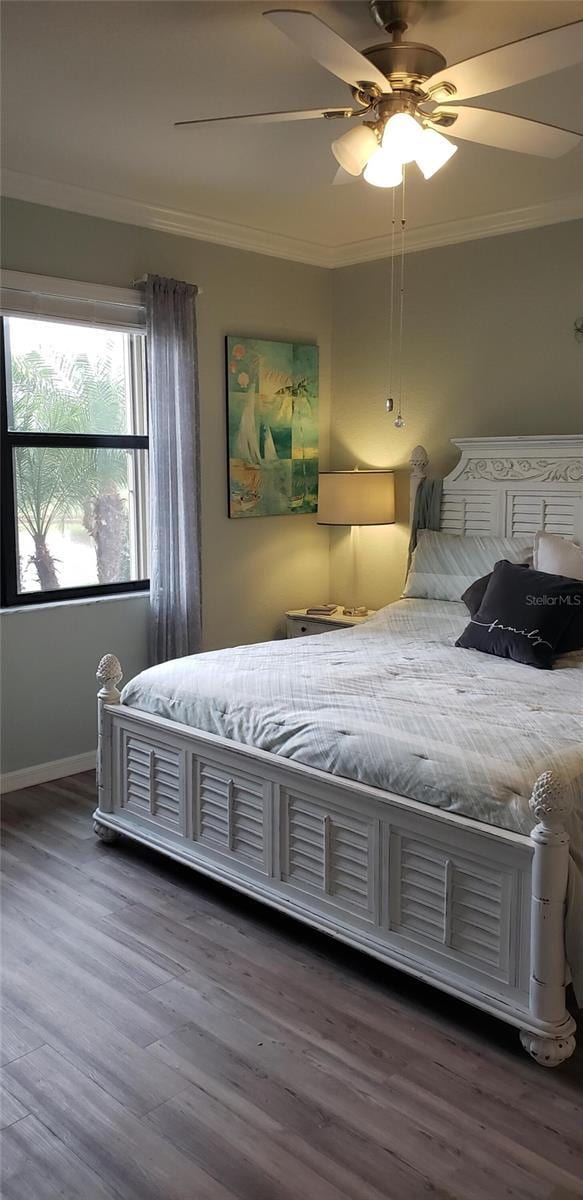 bedroom with ceiling fan, wood finished floors, and crown molding