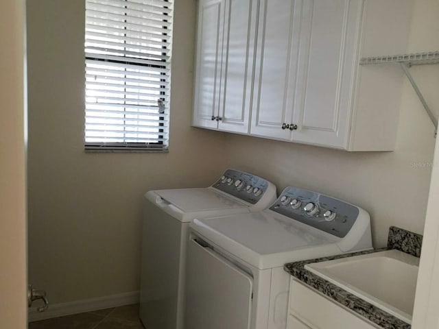 laundry area with cabinet space, baseboards, tile patterned floors, washing machine and clothes dryer, and a sink