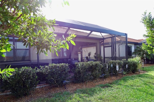 view of property exterior featuring a lanai and a lawn