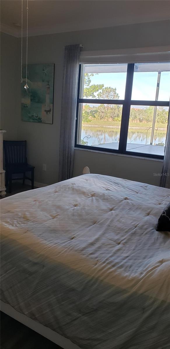 bedroom featuring a water view and crown molding