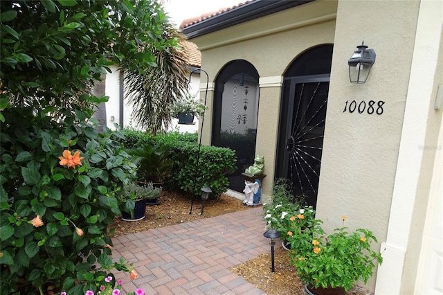 view of exterior entry featuring a tiled roof and stucco siding