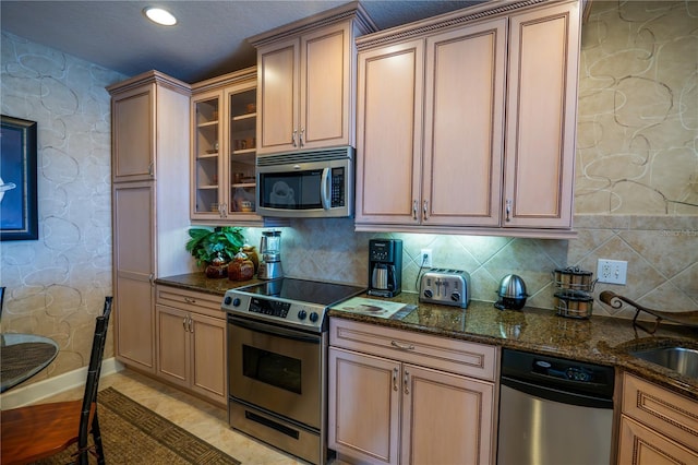 7500 Toscana Blvd Unit 341, Orlando, FL 32819 - kitchen featuring stainless steel appliances, dark stone countertops, glass insert cabinets, and decorative backsplash