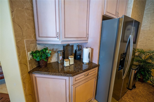 kitchen featuring stainless steel fridge, light brown cabinets, and dark stone counters