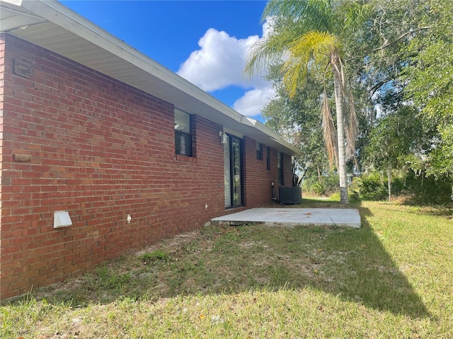 view of property exterior with central AC unit, a yard, and a patio