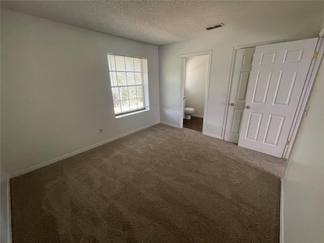 unfurnished bedroom featuring carpet, a textured ceiling, and ensuite bathroom