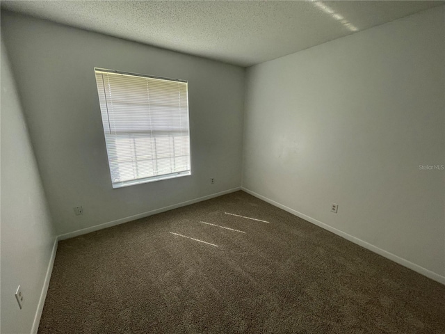 unfurnished room with dark carpet and a textured ceiling