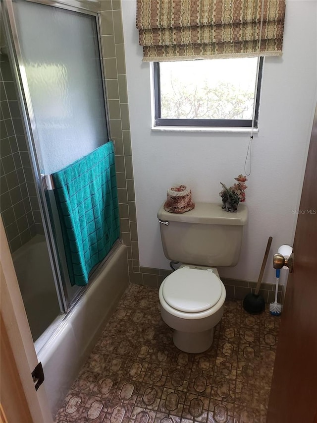 bathroom with shower / bath combination with glass door and toilet