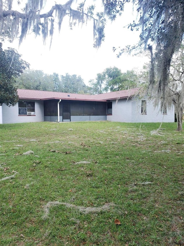 back of property with a yard and a sunroom