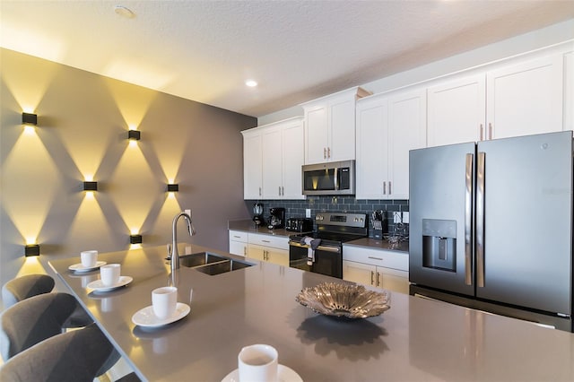 kitchen featuring sink, stainless steel appliances, backsplash, a textured ceiling, and white cabinets