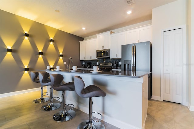 kitchen featuring white cabinets, appliances with stainless steel finishes, and a kitchen breakfast bar