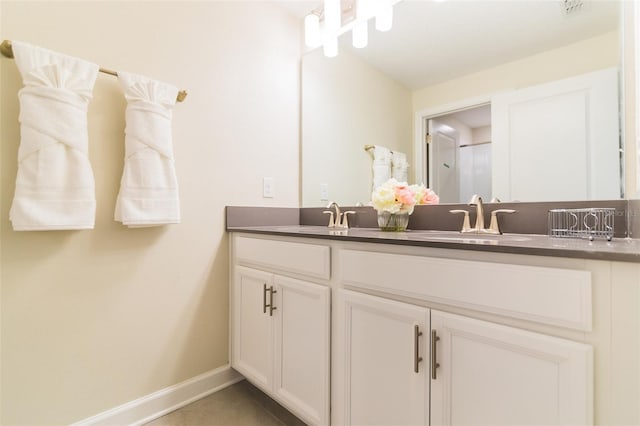 full bath featuring baseboards, double vanity, and tile patterned flooring