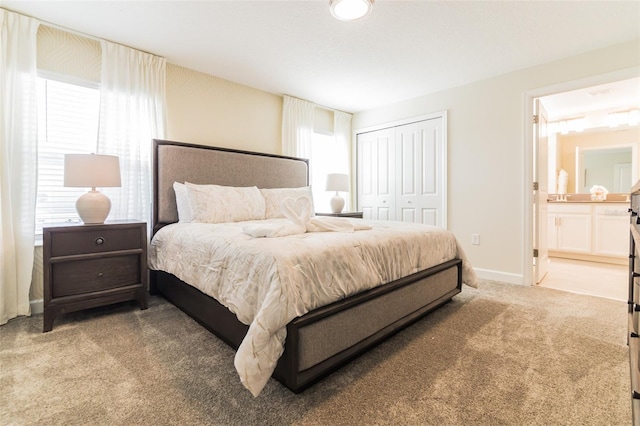bedroom with light colored carpet, a closet, and connected bathroom
