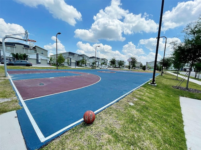 view of basketball court featuring a lawn, community basketball court, and a residential view