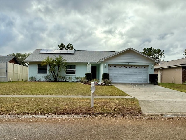 ranch-style home with a front yard, solar panels, and a garage