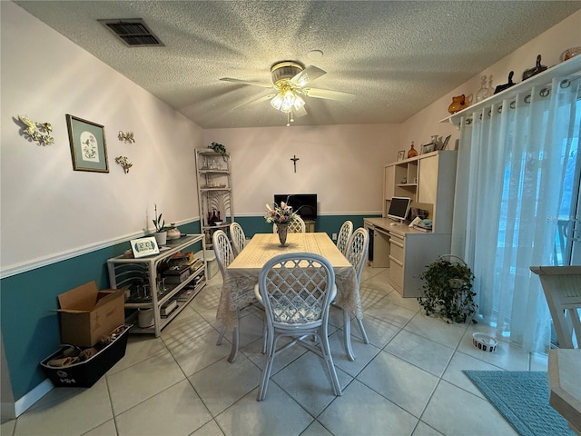 tiled dining area with ceiling fan and a textured ceiling