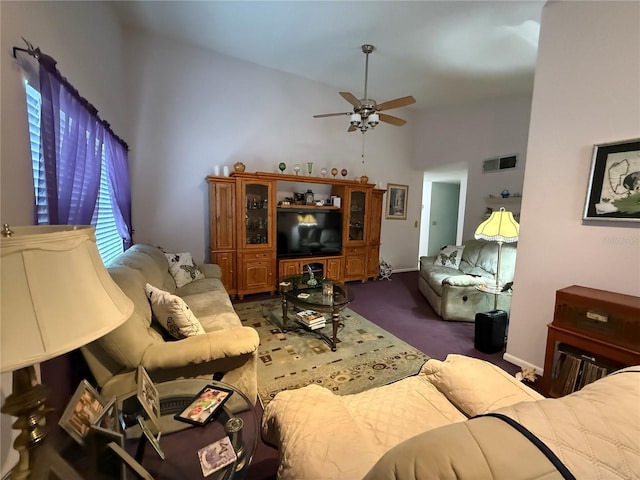 living room featuring dark colored carpet, ceiling fan, and a high ceiling