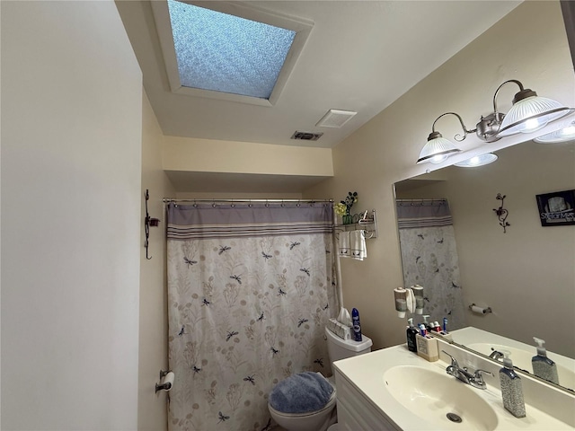 bathroom with a shower with curtain, vanity, toilet, and a skylight