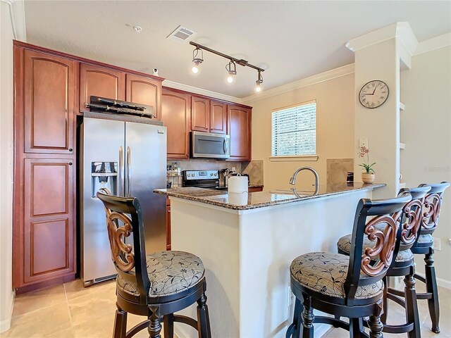 904 Charo Pkwy Unit 525, Davenport, FL 33897 - kitchen with stainless steel appliances, a kitchen bar, dark stone countertops, a peninsula, and ornamental molding