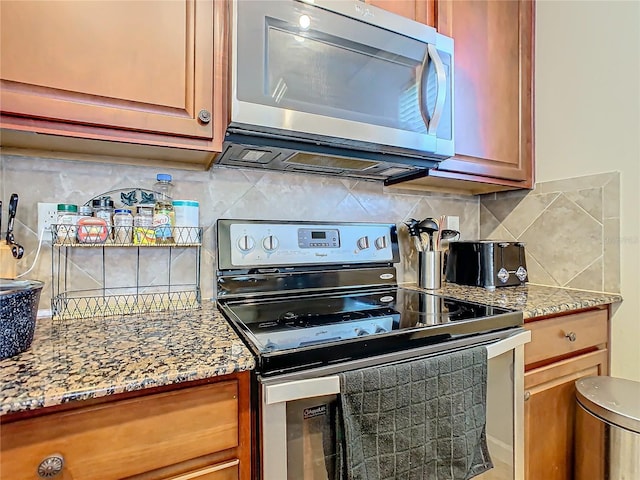 kitchen with decorative backsplash, light stone countertops, and appliances with stainless steel finishes