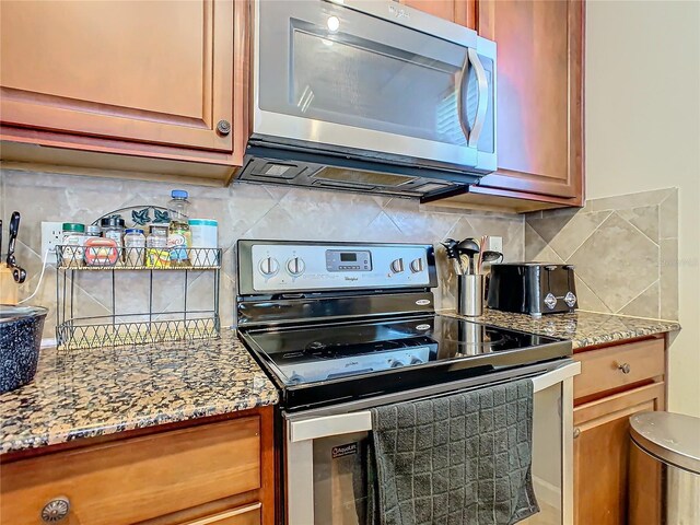 904 Charo Pkwy Unit 525, Davenport, FL 33897 - kitchen featuring stainless steel appliances, decorative backsplash, light stone countertops, and brown cabinets