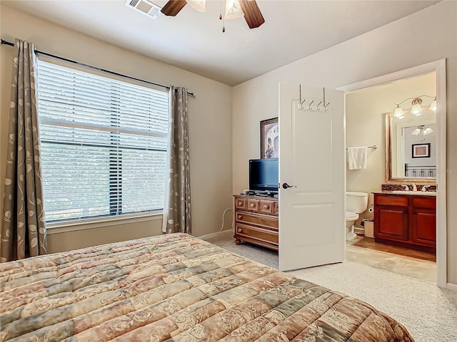 bedroom with multiple windows, ensuite bathroom, sink, and ceiling fan