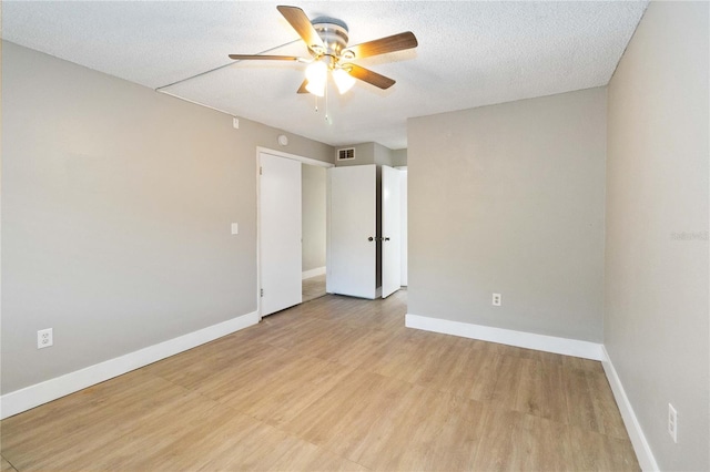 empty room featuring ceiling fan, light hardwood / wood-style floors, and a textured ceiling