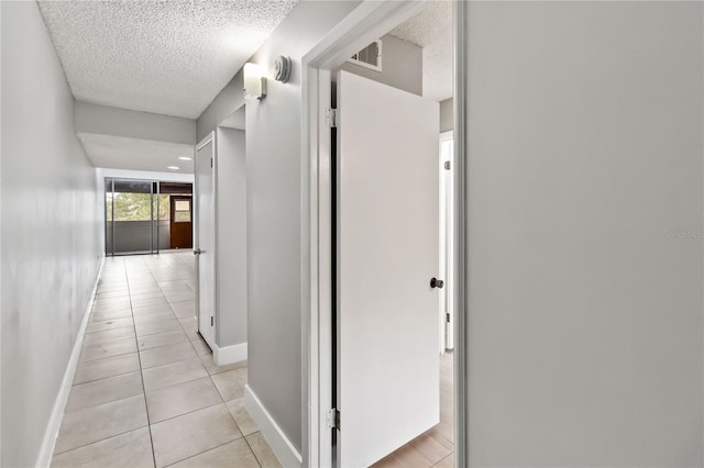 hallway featuring light tile patterned floors and a textured ceiling