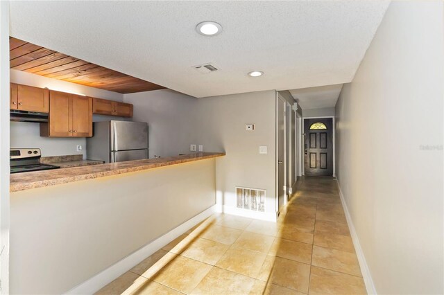 kitchen featuring appliances with stainless steel finishes, brown cabinetry, visible vents, and under cabinet range hood