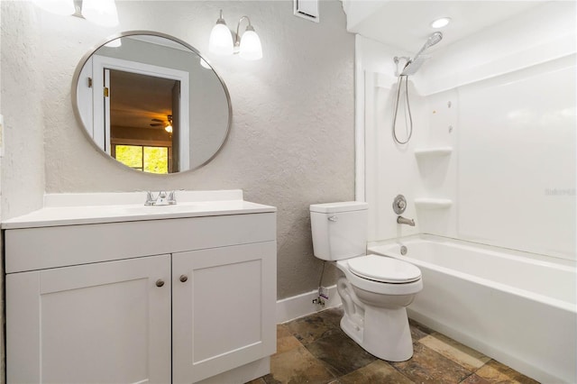 bathroom featuring toilet, stone tile floors, vanity, and a textured wall