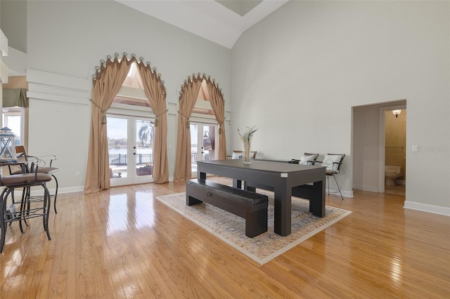 game room featuring light wood-type flooring, high vaulted ceiling, and french doors